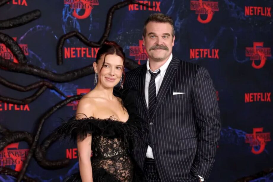 Millie bobby brown wows in a sheer naked lace dress while arm in arm with david harbour amid cast controversy